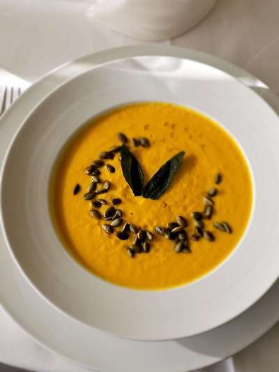 Butternut Squash Soup in a white bowl garnished with Pepitas and Sage leaf
