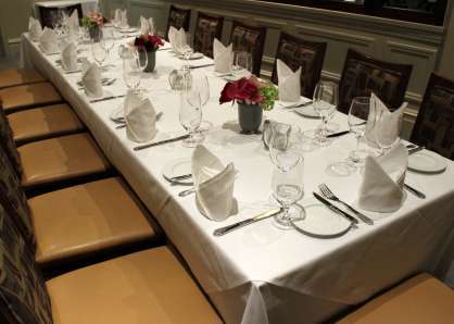 Closeup of a long, 20-person table, with full place settings, cloth napkins, and flowers in the Wine Room and 