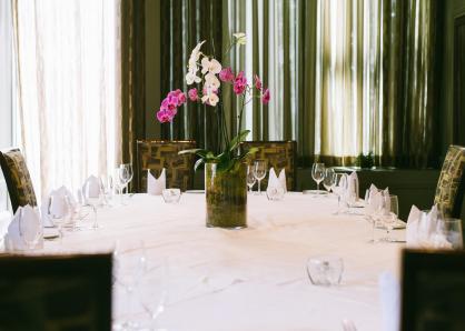 Table set for eight with white tablecloth and a centerpiece of pink orchids