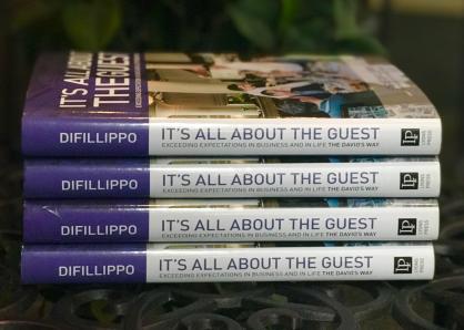A stack of four hardback copies of Steve DiFillippo's book, It's All About the Guest
