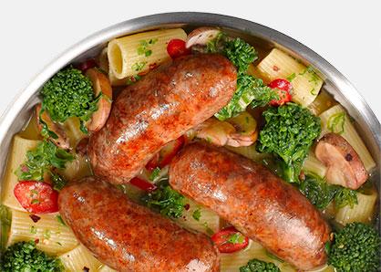 Davio's hot Italian sausages browned in a pan with ziti, broccoli florets, sliced mushrooms, and halved grape tomatoes
