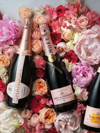 3 bottles of champagne on a bed of roses (red, white, pink, orange)