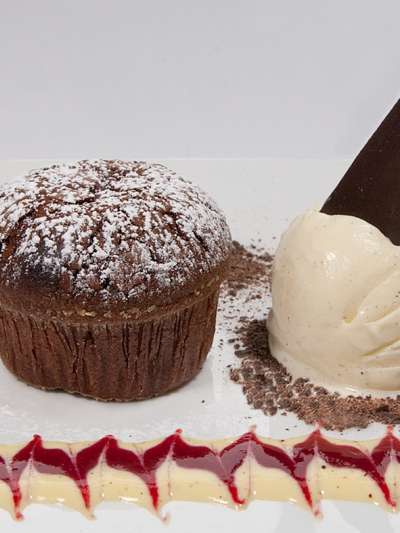 Warm chocolate cake dusted with powdered sugar, vanilla bean ice cream, creme anglaise, raspberry glace
