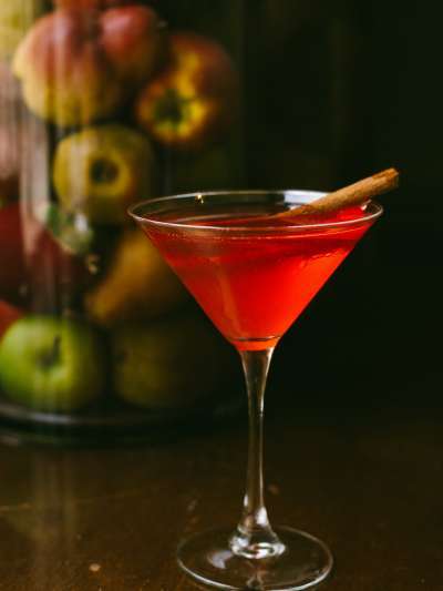 apple martini in martini glass with cinnamon stick and apples behind photo