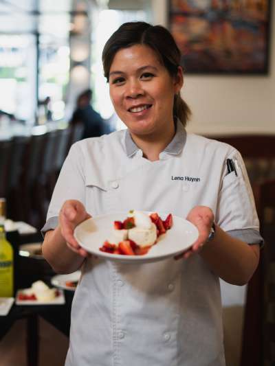 Woman, dark hair, holding a dessert with fruit