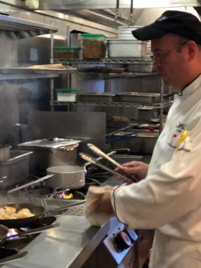 Luis Peres, in chef's whites and a back Davio's baseball cap, tosses gnocchi in a pan on a gas range in the Davio's kitchen