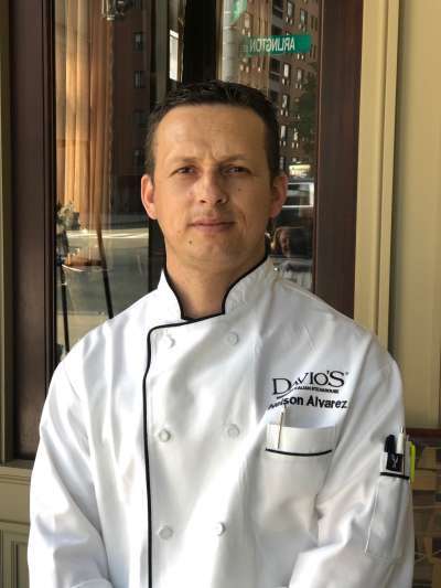 Nelson Alvares poses in chefs whites outside the restaurant, with Arlington Street reflected in the window behind him