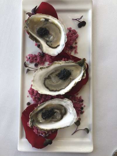 Three oysters on the half shell with caviar, on a bed of rose petals
