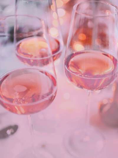 Light reflects off of many glasses of rosé on a table covered with a white tablecloth