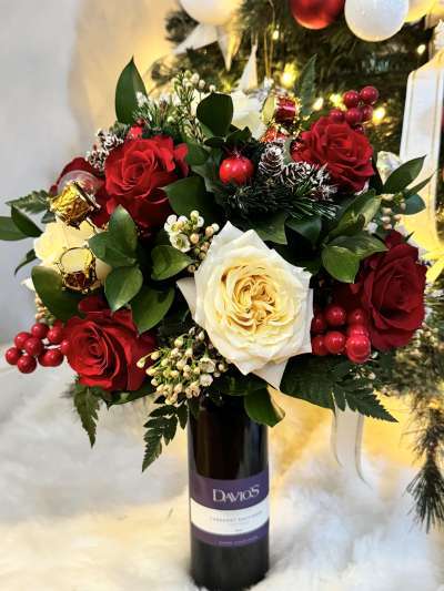 Red and white flowers with berries in a Davio's wine bottle