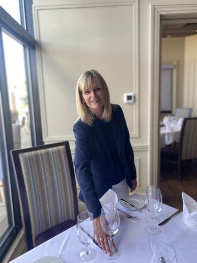 Woman, Blond Hair, Blue Jacket, adjusting a napkin on a table