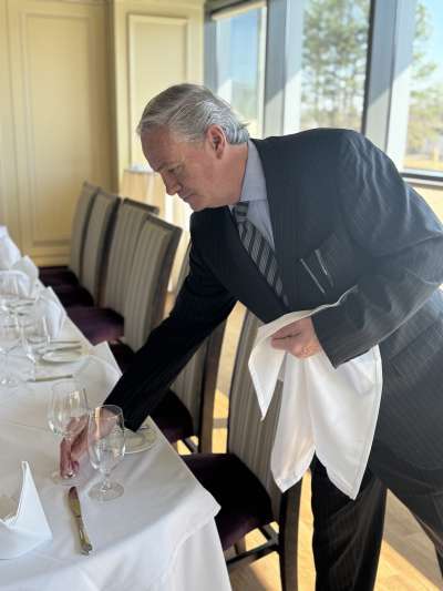 Man leaning over a table cleaning glassware
