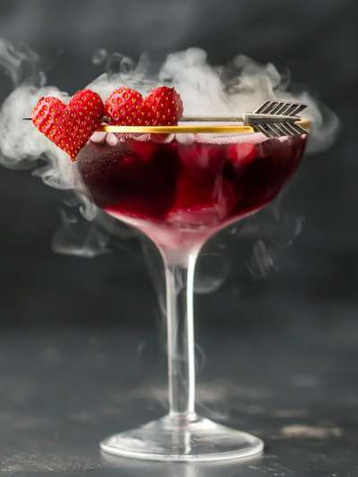 Valentine cocktail, 2 red hearts as garnish, smoke coming from martini glass