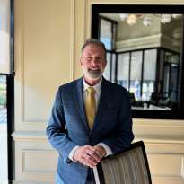 Man Blue Suit, Standing, leaning on a chair