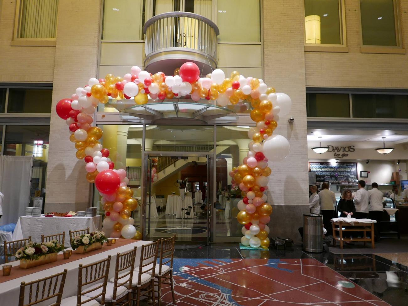 A colorful arch of red, pink, yellow, and white balloons surrounds the entrance to the Galleria lobby space