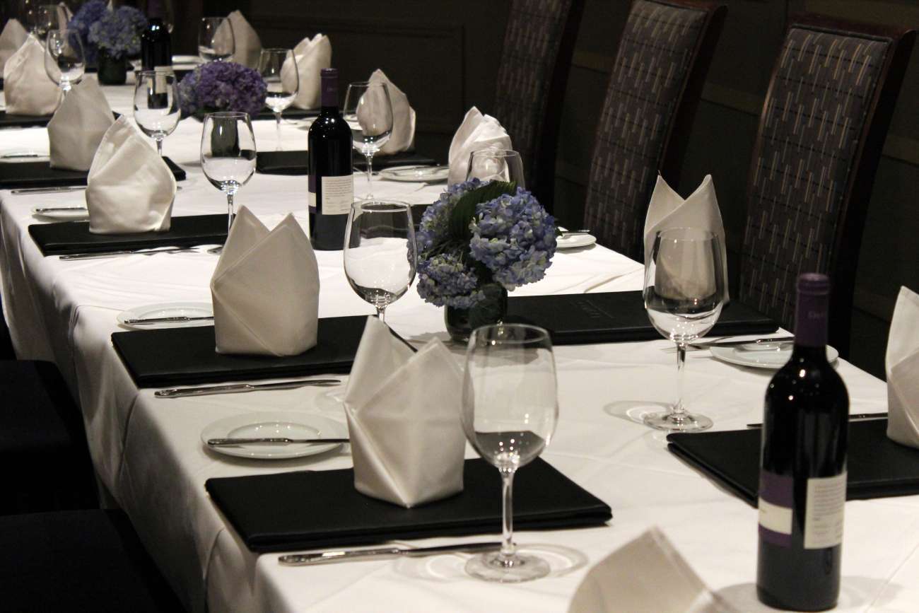 Closeup of long table set with menus, napkins folded into crown shapes, and blue hydrangea centerpieces