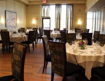The Walnut Room has paneled walls, round tables, high-backed upholstered chairs, and and tall windows with sheer curtains