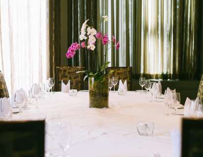 Table set for eight with white tablecloth and a centerpiece of pink orchids