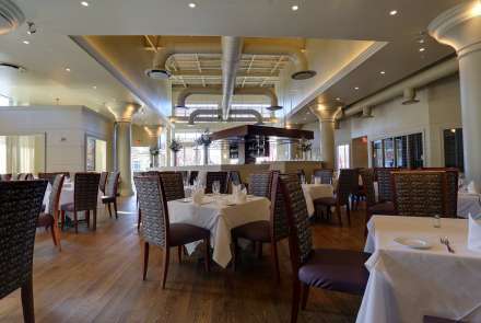 The main dining room features high ceilings, majestic columns with period cornice moldings, large wall-to-wall windows and hardwood floors