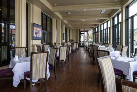 Square tables in a long room with Floor to Ceiling Glass Windows