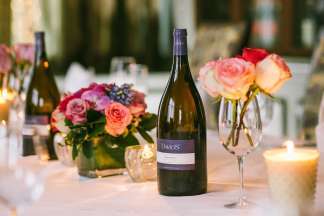 Table set with Davio's-labeled wine and wine glasses; red, pink and purple flowers; and lit candles.