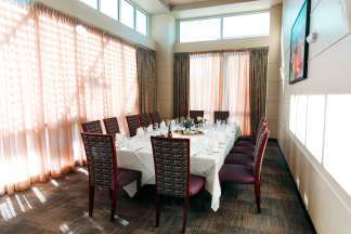 The Washington Room with an oblong table set for twelve. Sheer curtains and clerestory windows provide privacy while letting in light.